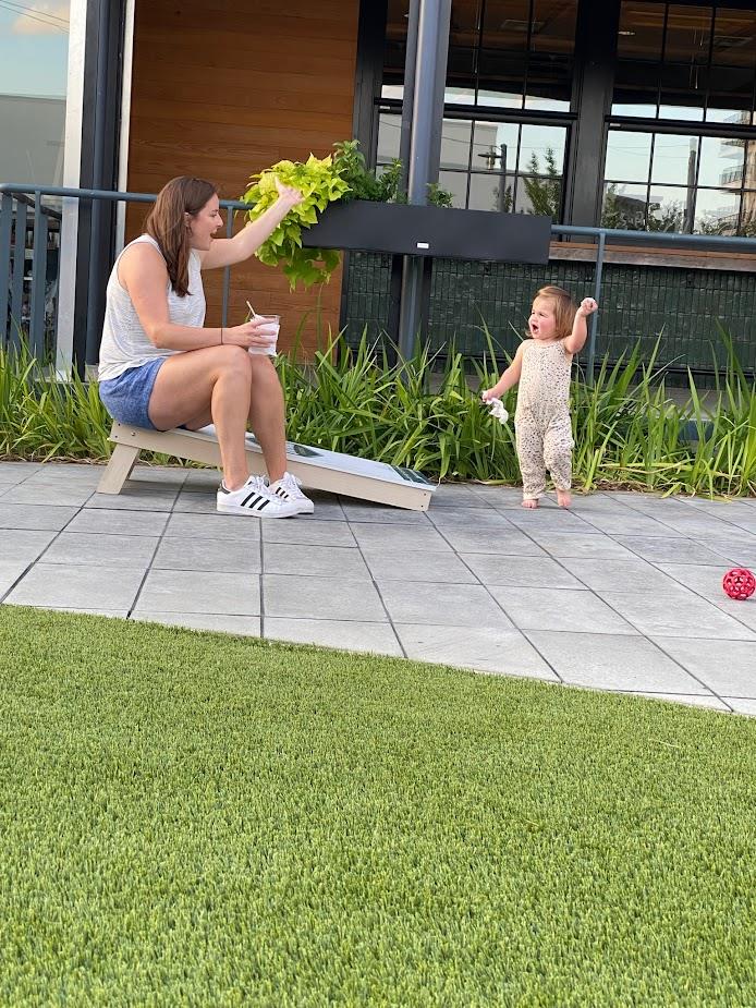 sitting woman and standing toddler tossing ball outdoors